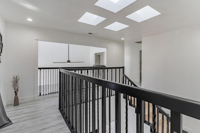 hall featuring a skylight and light hardwood / wood-style flooring