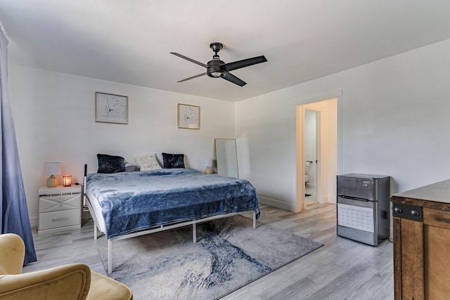 bedroom featuring ceiling fan, ensuite bath, stainless steel refrigerator, and light hardwood / wood-style flooring