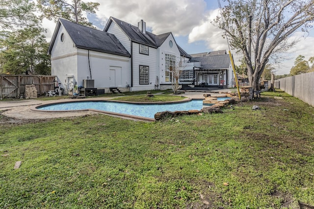 rear view of house with a fenced in pool and a yard