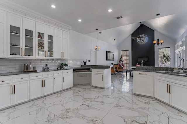 kitchen with decorative light fixtures, kitchen peninsula, sink, and tasteful backsplash