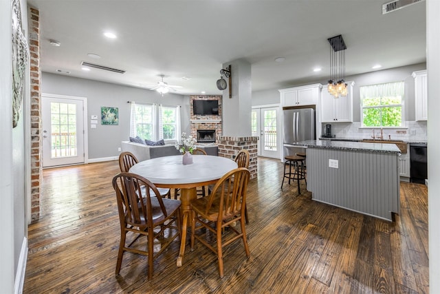 dining space with a fireplace, plenty of natural light, and dark hardwood / wood-style floors