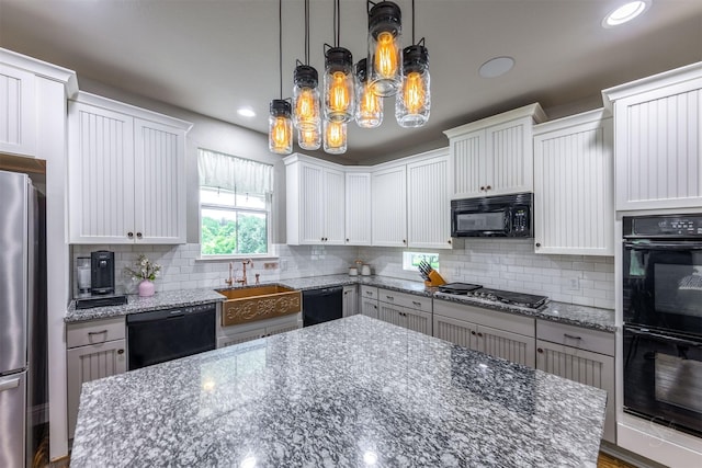 kitchen featuring white cabinetry, tasteful backsplash, light stone counters, decorative light fixtures, and black appliances