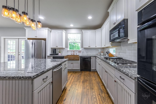 kitchen with black appliances, plenty of natural light, a kitchen island, and dark wood-type flooring