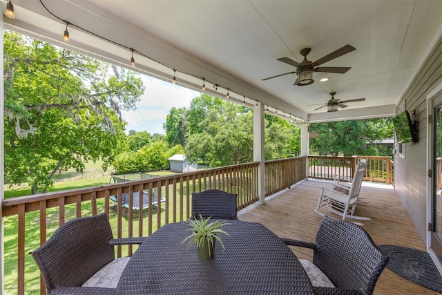 wooden terrace with ceiling fan and a yard