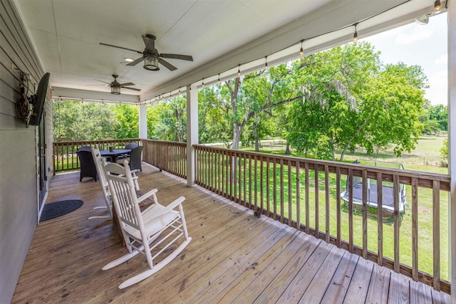 wooden terrace with a lawn and ceiling fan