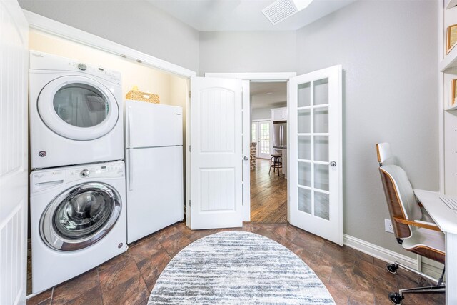 clothes washing area featuring french doors, dark hardwood / wood-style flooring, and stacked washer / drying machine