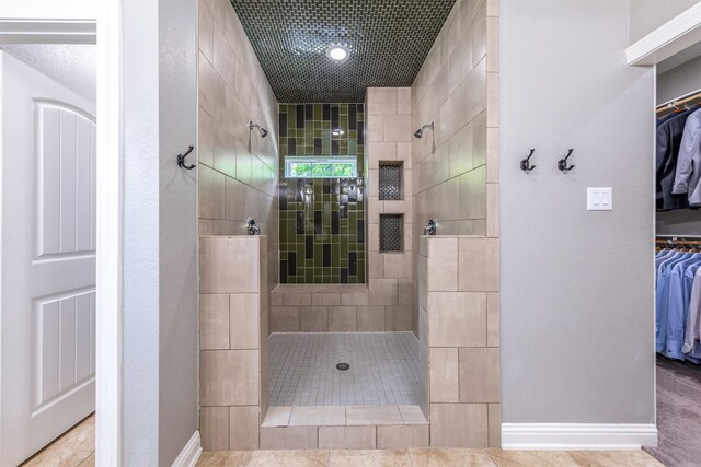 bathroom with a tile shower and tile patterned floors