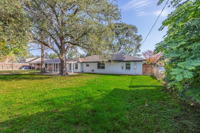 back of property featuring a lawn and solar panels