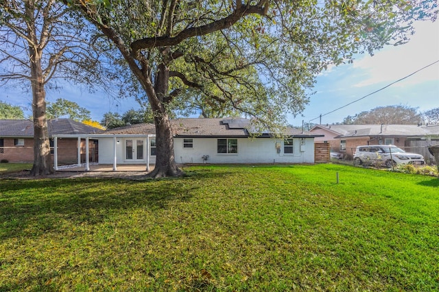 back of property with a lawn, solar panels, and french doors