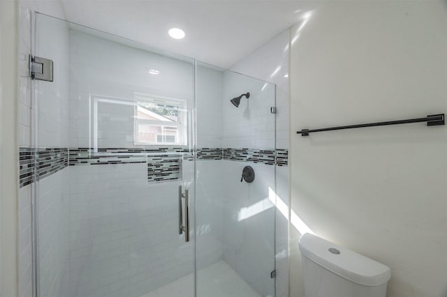 bathroom with a shower with shower door and toilet