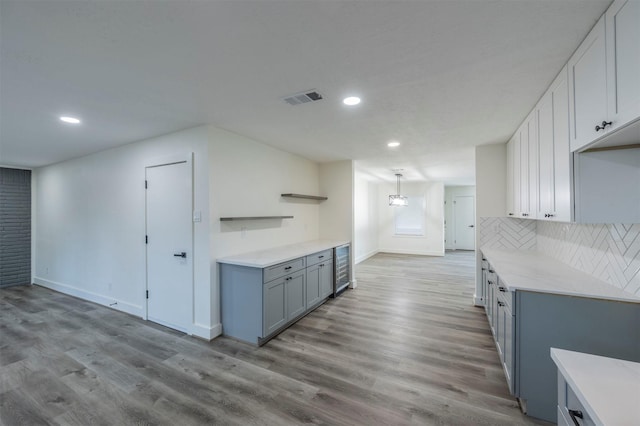 kitchen featuring white cabinets, backsplash, light hardwood / wood-style flooring, and beverage cooler