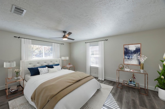 bedroom with ceiling fan, dark wood-type flooring, and a textured ceiling