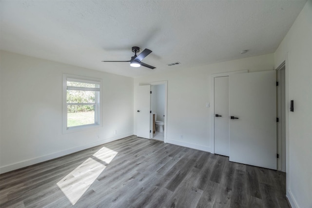 unfurnished bedroom with connected bathroom, ceiling fan, hardwood / wood-style floors, a textured ceiling, and a closet