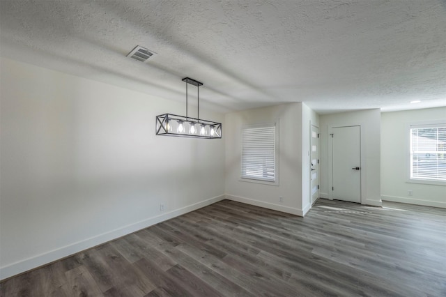 unfurnished dining area with a textured ceiling and dark wood-type flooring