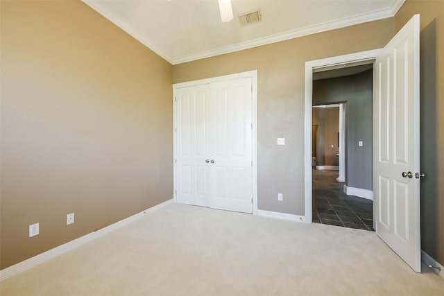 unfurnished bedroom featuring carpet flooring, ceiling fan, a closet, and ornamental molding