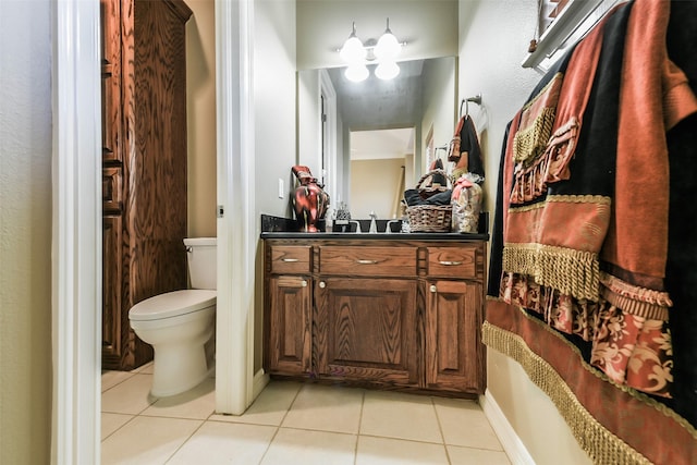 bathroom featuring tile patterned floors, vanity, toilet, and an inviting chandelier