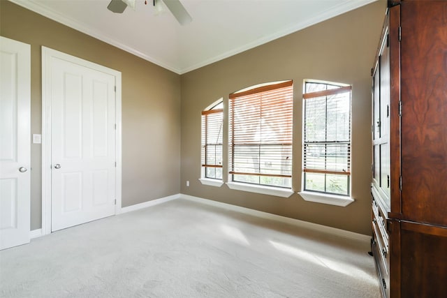 unfurnished bedroom featuring ceiling fan, crown molding, and light colored carpet