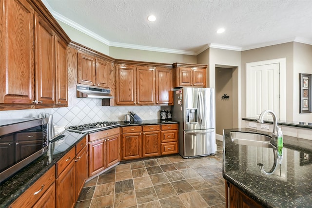 kitchen with sink, stainless steel appliances, dark stone counters, a textured ceiling, and decorative backsplash