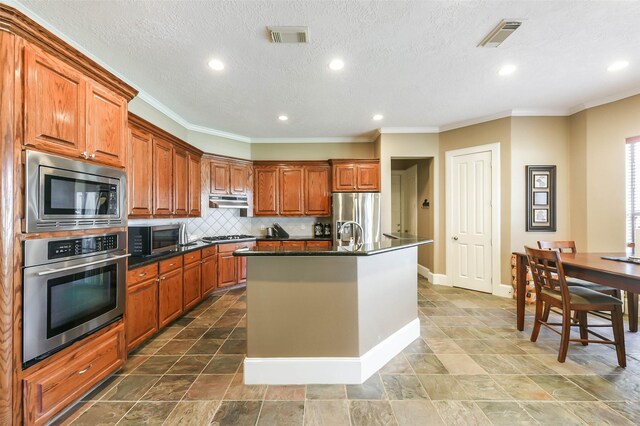 kitchen with decorative backsplash, stainless steel appliances, ornamental molding, and an island with sink