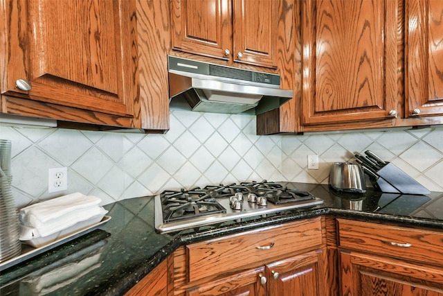 kitchen with backsplash, dark stone counters, and stainless steel gas stovetop