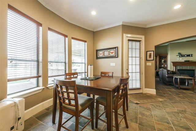 dining room featuring a tiled fireplace and crown molding