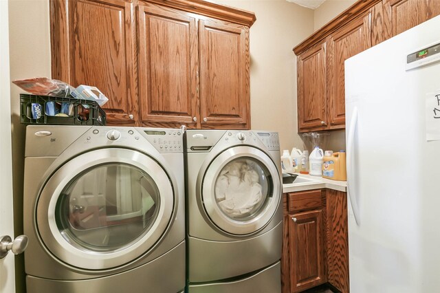 clothes washing area featuring cabinets and separate washer and dryer