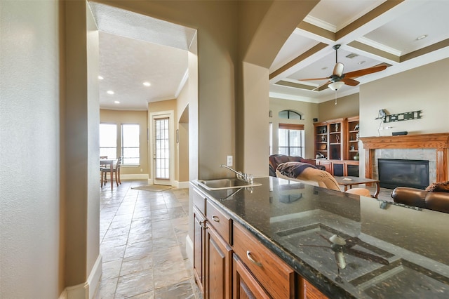 kitchen featuring ornamental molding, coffered ceiling, sink, beam ceiling, and dark stone countertops