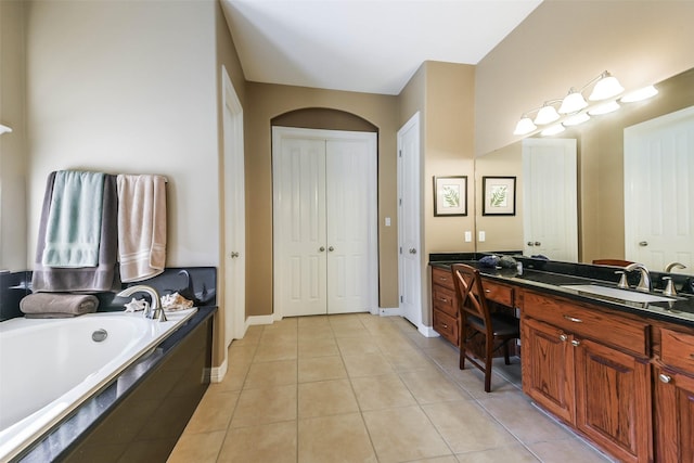 bathroom with tile patterned flooring, vanity, and tiled bath