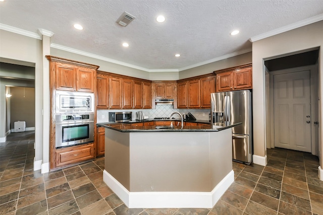 kitchen with tasteful backsplash, a textured ceiling, stainless steel appliances, a kitchen island with sink, and dark stone countertops