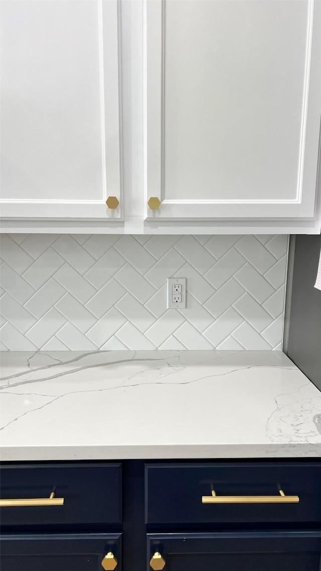 kitchen with decorative backsplash, white cabinetry, and light stone countertops