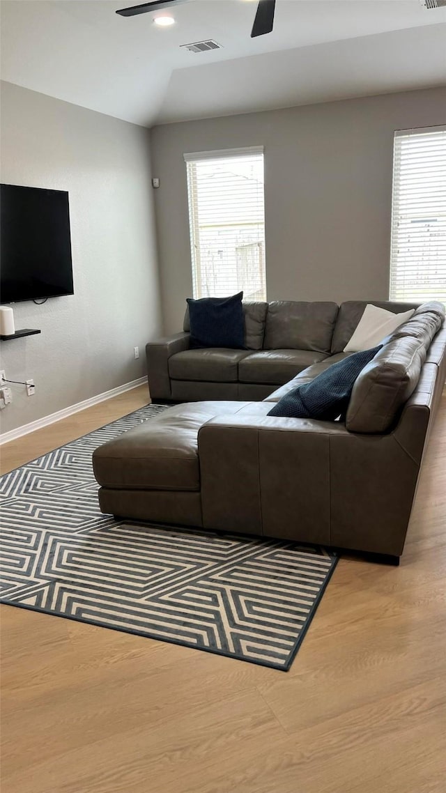 living room featuring ceiling fan, light hardwood / wood-style flooring, vaulted ceiling, and plenty of natural light