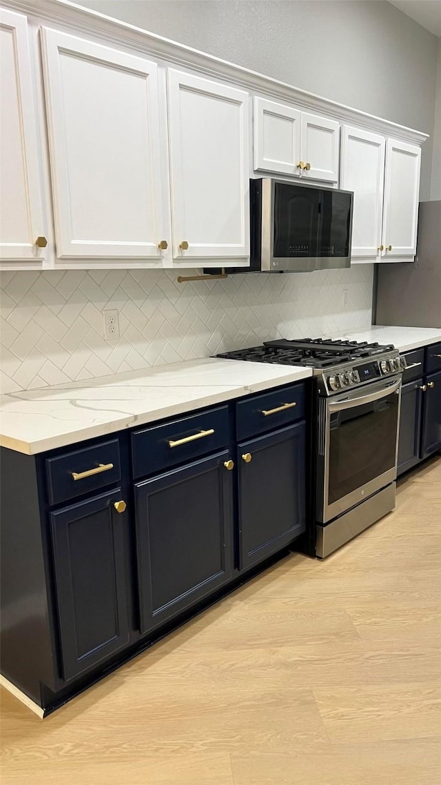 kitchen featuring white cabinets, appliances with stainless steel finishes, light hardwood / wood-style flooring, and tasteful backsplash