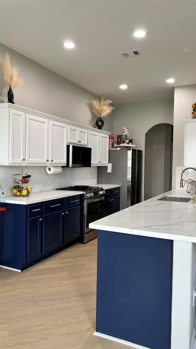 kitchen featuring light hardwood / wood-style flooring, backsplash, white cabinetry, blue cabinets, and appliances with stainless steel finishes