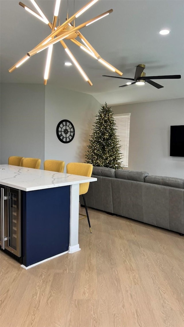 unfurnished living room featuring ceiling fan, light hardwood / wood-style flooring, and wine cooler