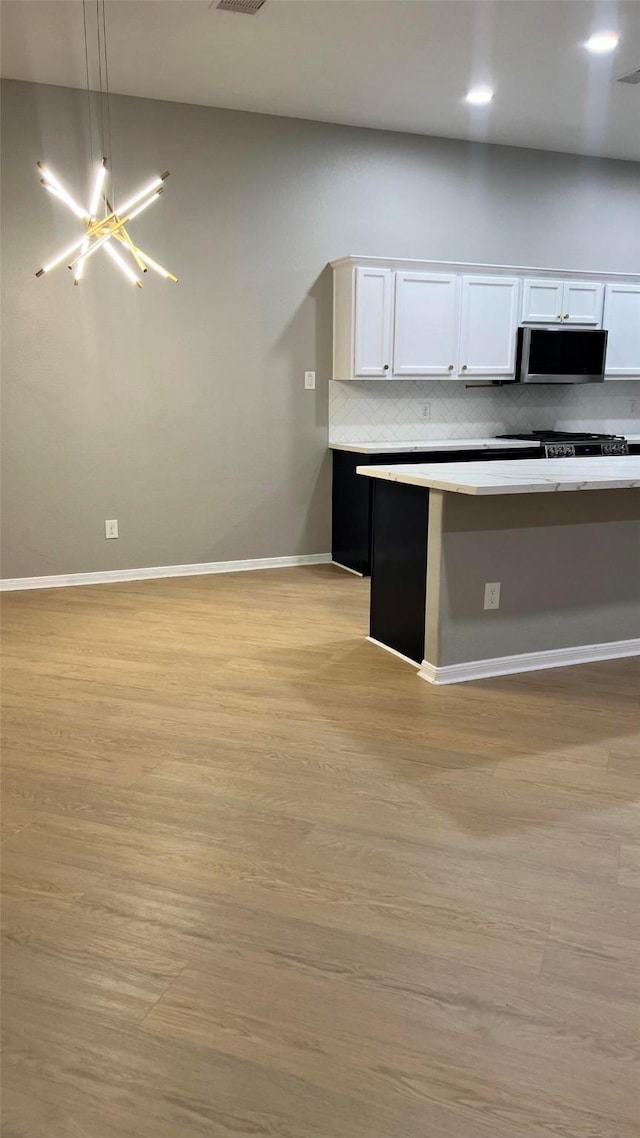 kitchen featuring decorative light fixtures, white cabinets, tasteful backsplash, and light hardwood / wood-style floors