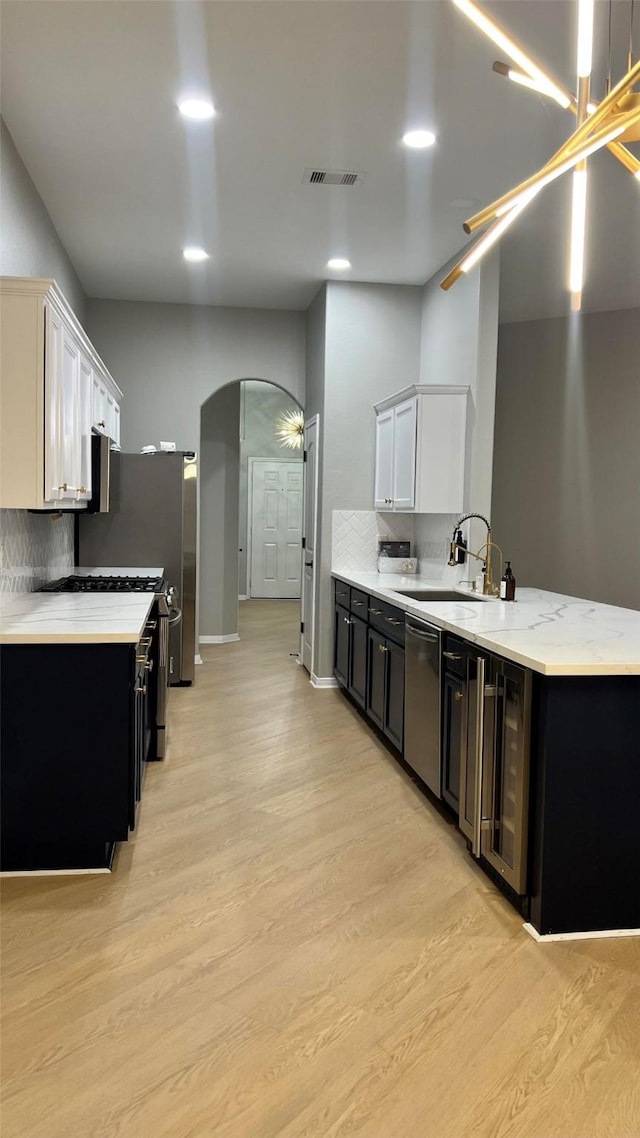 kitchen with sink, white cabinetry, dishwasher, light hardwood / wood-style flooring, and backsplash