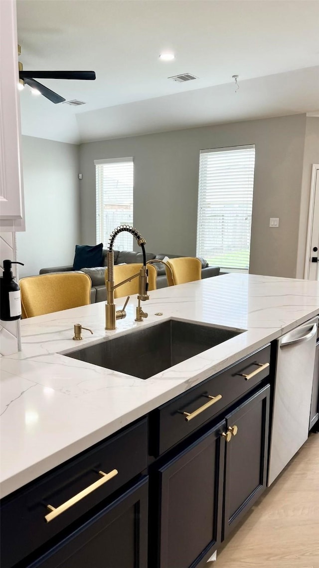 kitchen with light stone countertops, dishwasher, light hardwood / wood-style floors, and sink