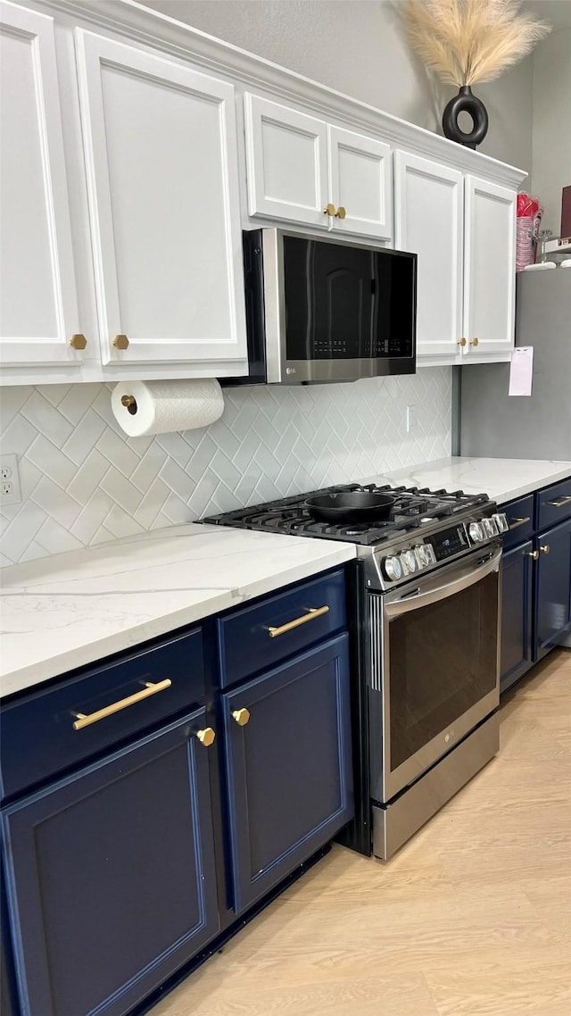 kitchen with white cabinets, stainless steel appliances, and blue cabinetry