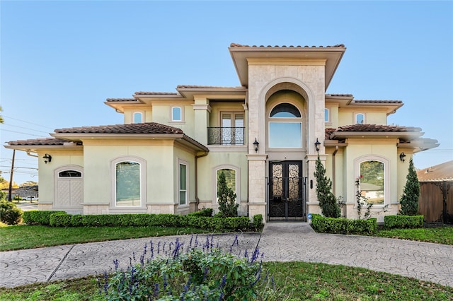 mediterranean / spanish-style home with a balcony and french doors