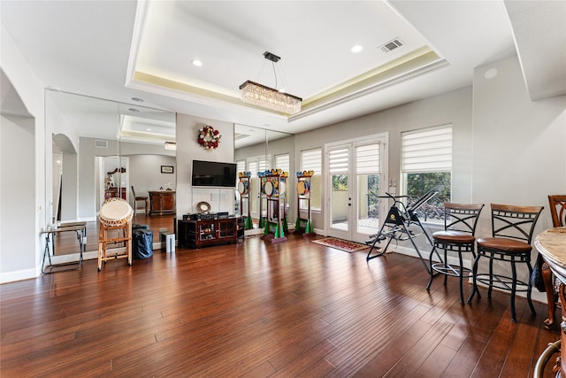 interior space with a raised ceiling, dark hardwood / wood-style floors, and french doors