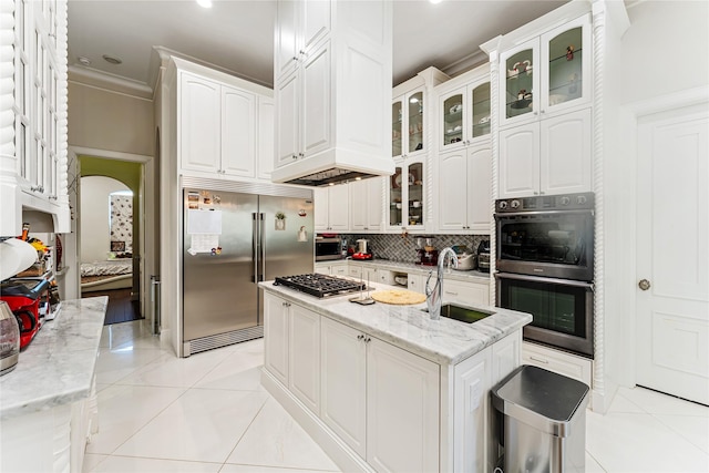 kitchen featuring sink, light stone counters, a center island with sink, stainless steel appliances, and white cabinets