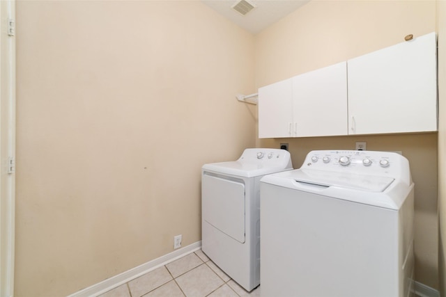 laundry area with light tile patterned flooring, cabinets, and independent washer and dryer