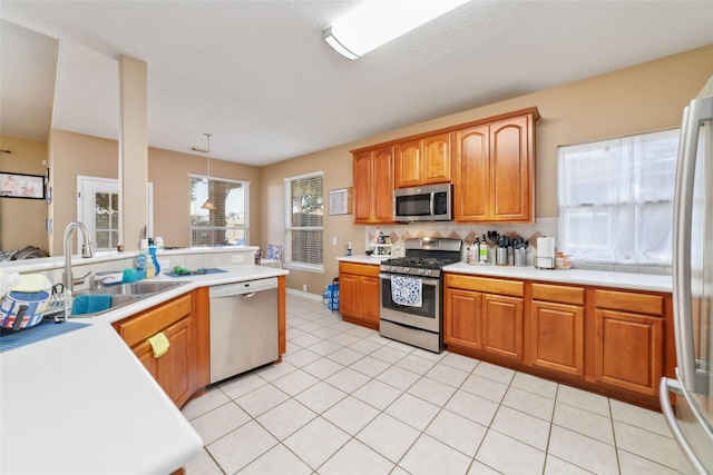 kitchen featuring pendant lighting, backsplash, sink, appliances with stainless steel finishes, and light tile patterned flooring