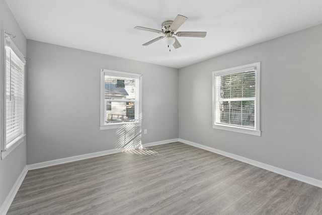 empty room featuring ceiling fan, plenty of natural light, and light hardwood / wood-style floors