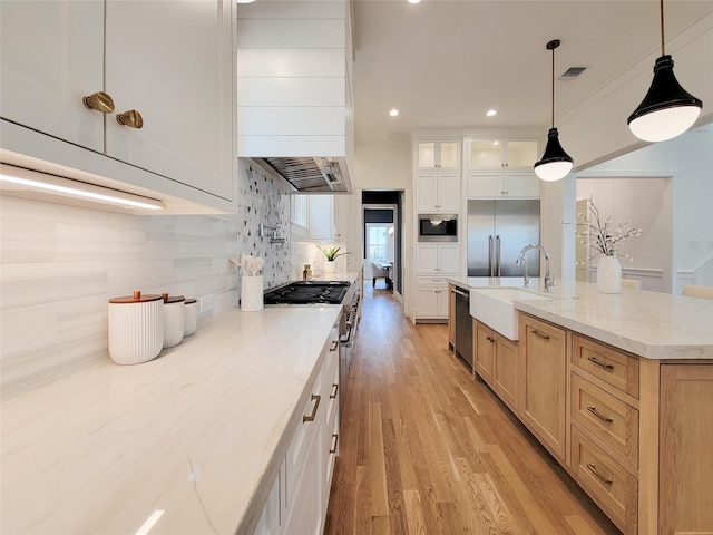 kitchen featuring pendant lighting, sink, white cabinetry, built in appliances, and light stone countertops