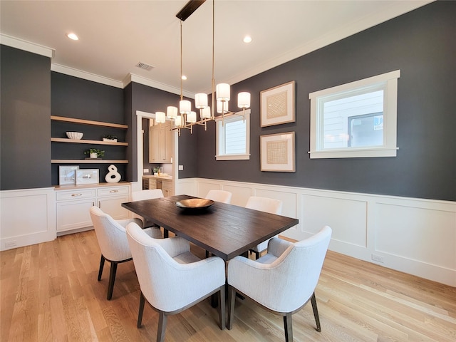 dining space featuring an inviting chandelier, crown molding, and light wood-type flooring