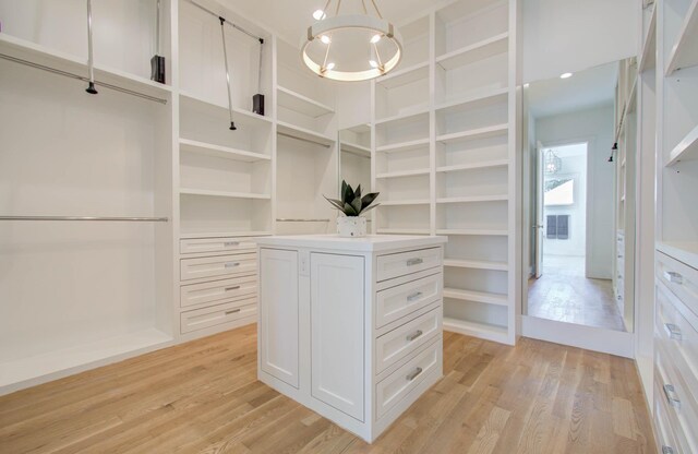 walk in closet featuring an inviting chandelier and light wood-type flooring