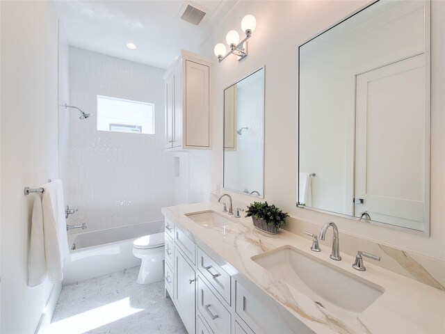 full bathroom featuring vanity, tiled shower / bath, and toilet