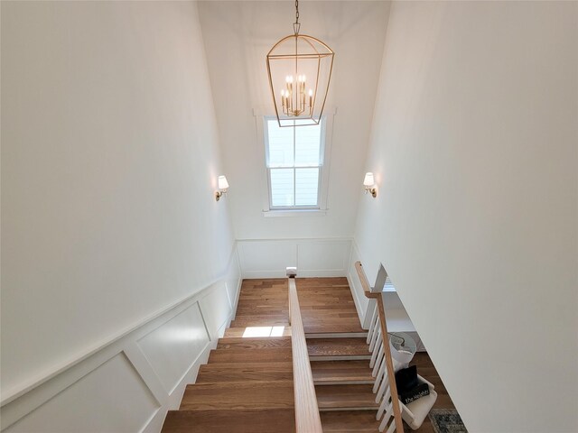 staircase featuring hardwood / wood-style floors and a notable chandelier