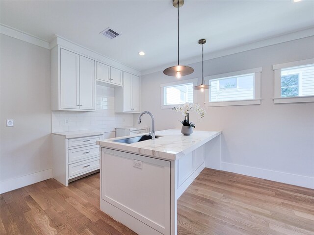 kitchen with sink, white cabinetry, tasteful backsplash, hanging light fixtures, and light wood-type flooring